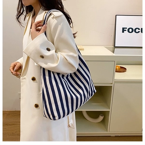 Mannequin portant un grand sac cabas en toile rayé bleu et blanc dans une pièce