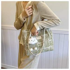 Detail of woven tote bag with a leather label and a cute plush cloud charm accessory