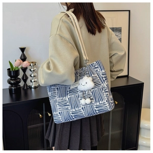 Detail of canvas tote bag with blue abstract patterns and cloud plush charm accessory