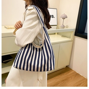 Détail du sac fourre-tout en toile à rayures bleues et blanches porté à l'épaule
