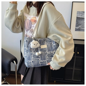 Detail of woven canvas tote with blue geometric patterns and cloud charm accessory