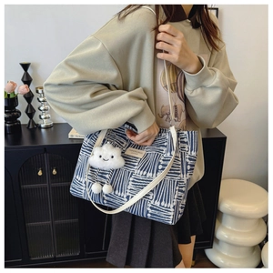 Detail of blue and white striped tote bag with plush cloud charm and slim shoulder strap