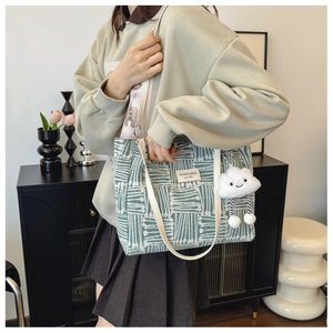 Canvas tote with green geometric pattern featuring a plush cloud charm and leather straps