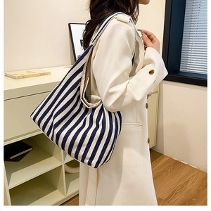 Vue détaillée du sac cabas en toile à rayures bleues et blanches porté avec un trench