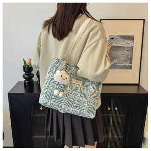 Detailed close-up of green and white geometric tote bag with plush cloud keychain accessory
