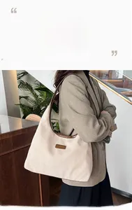 Detail of off-white corduroy tote bag with brown leather handles and brand patch