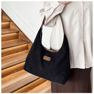 Detail of black corduroy tote bag featuring leather straps and branded vintage patch