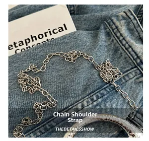 Close-up of polished silver metal chain strap and textured handle on denim background