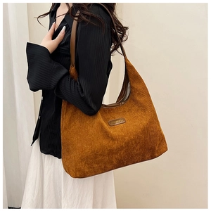 Detail of soft brown corduroy tote bag featuring leather logo patch and shoulder strap