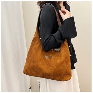 Detail of caramel corduroy tote bag texture and leather patch on shoulder bag