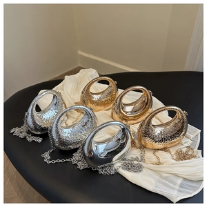 Detailed display of silver and gold crescent bags with chain straps on white satin fabric