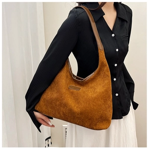 Close-up of brown corduroy hobo bag with leather strap worn by model for winter style
