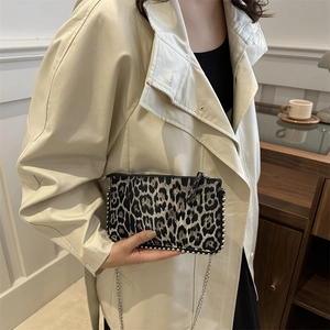 Chic leopard print crossbody bag with silver studs and chain strap on a model
