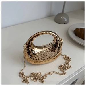 Detail of gold crescent handbag with oval texture and detachable chain strap