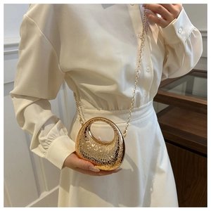 Close-up of golden textured mini handbag with metallic finish and delicate chain strap