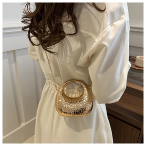Golden moon evening bag with hammered texture shown on model wearing white dress
