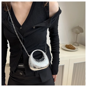 Detailed view of mini silver crescent bag with hammered texture and delicate metal chain
