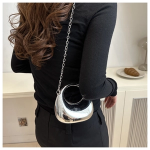 Mirror silver semi-circle chain bag shown on a model in a minimalist setting