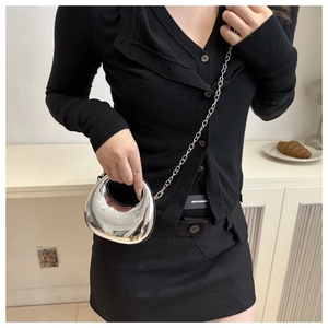 Close-up of a futuristic silver metallic crescent bag with chain strap on a model