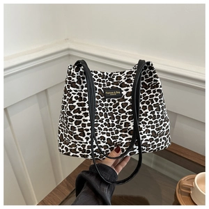 Dettaglio della borsa tote leopardata con etichetta in pelle nera e testo dorato