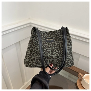 Dettaglio della borsa tote leopardata verde con toppa in pelle nera e spalline doppie