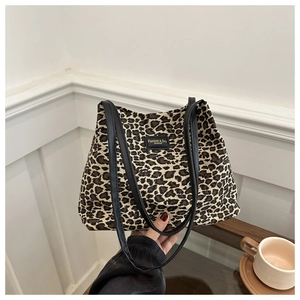 Dettaglio della borsa tote leopardata con cinturini in pelle nera e toppa con logo