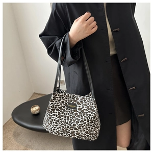 Dettaglio della borsa tote leopardata alla moda con tracolla nera e logo con etichetta