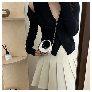 Mini mirror silver egg-shaped chain bag held by model wearing a black knit sweater
