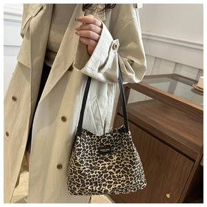 Dettaglio ravvicinato della borsa tote leopardata in tela con patch in pelle nera e manico