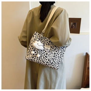 Close-up of leopard print canvas tote with adjustable strap and white cloud charm