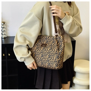 Close-up of leopard print tote bag with brown leather straps and metallic ring detail