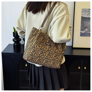 Detailed shot of leopard print tote bag with brown leather strap worn by a model