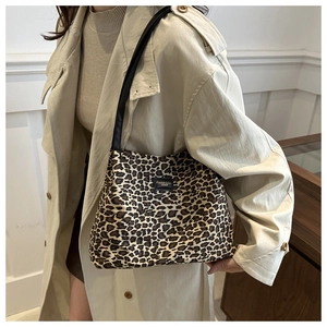 Borsa tote leopardata con cinturini in pelle nera indossata su un trench beige
