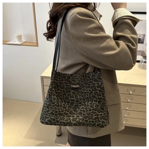 Dettaglio della borsa tote in tela leopardata con manici in pelle e piastrina del logo