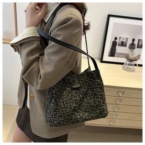 Dettaglio della borsa tote leopardata con spalline in pelle nera indossata da modella