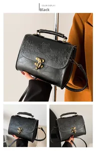 Detail of vintage embossed black crossbody bag with bronze floral clasp and top handle