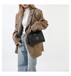 Detail of black vintage crossbody bag with floral embroidery and antique bronze clasp