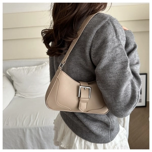 Detailed side view of beige crescent underarm bag with silver buckle worn by a model