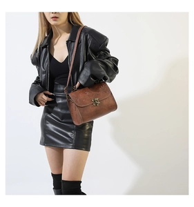 Detail of vintage brown leather bag with embossed texture and antique bronze metal clasp