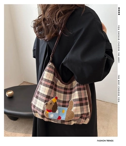 Close-up of retro plaid bag featuring a cute teddy bear plush embroidery with leather strap