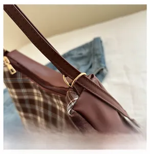 Detailed close-up of premium gold metal rings and stitching on a plaid shoulder bag