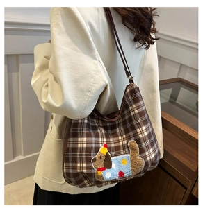 Detail of plaid canvas shoulder bag featuring a cute cartoon puppy plush embroidery