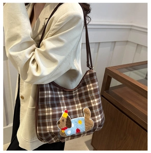 Detail of plaid crossbody bag featuring a cute cartoon dog patch on a textured brown fabric