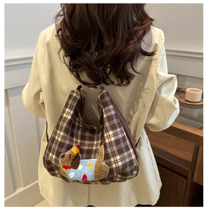 Detail of checkered crossbody bag featuring a cute plush dog patch and leather handle