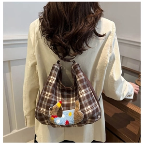 Detail of checkered hobo bag with colorful cartoon puppy embroidery and leather strap