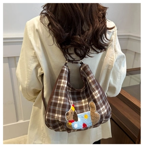 Brown plaid hobo bag with cartoon puppy embroidery worn by model over a white blazer
