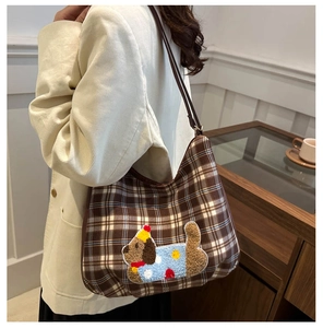 Brown checkered tote bag with embroidered dog patch shown on model in home setting