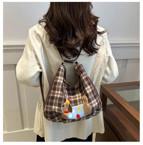 Detailed view of brown checkered crossbody bag featuring colorful cartoon dog embroidery