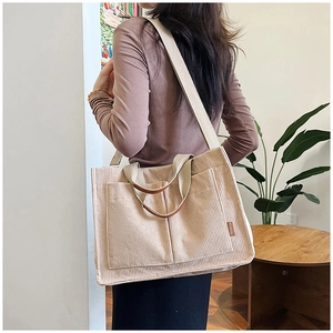 Detail of beige corduroy tote bag showing side pockets, brown handles and Fashion label