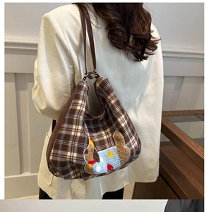 Detail of checkered tote bag featuring a 3D plush puppy patch with blue sweater design